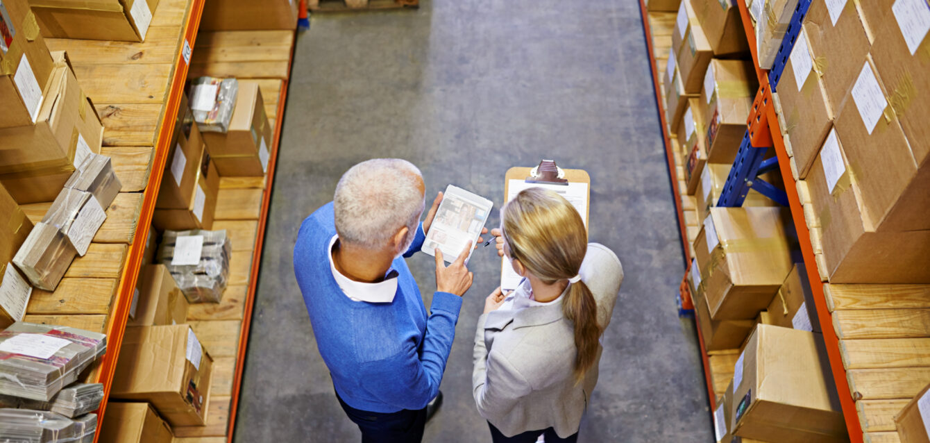 High angle shot of a two managers working on a digital tablet in a warehouse. High angle shot of a two managers working on a digital tablet in a warehouse.
